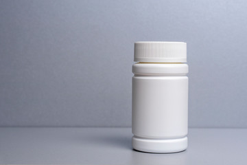1 white jar for medicines and vitamins and dietary supplements without a name are on a gray shelf. copy space to the left. layout for a pharmacy, a store