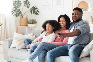 Smiling african american family relaxing and watching tv in living room
