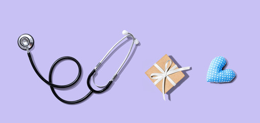 Stethoscope with a gift and a heart cushion - flat lay