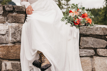 bride in white dress and hiking boots with bouquet of flowers