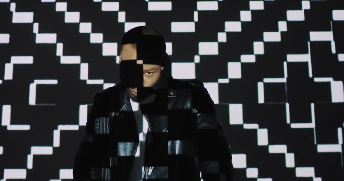 Handsome African American young male model dancer dancing on white wall with motley graphic projections and squares figures. Shooting in modern style. Man with projected plaid pattern.