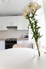 white lilies in a vase on the kitchen table
