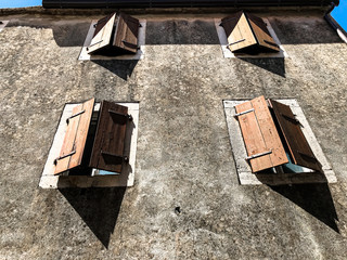 Windows in the old town. Window shutters on an old plastered wall. Suitable for illustrating the old cities of Italy, Croatia and others.