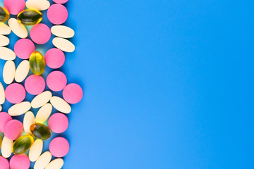  A lot of multi-colored pills on a blue background. Copy space