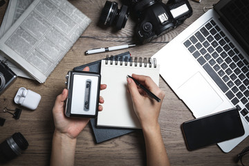 Journalist with voice recorder working at wooden table, top view
