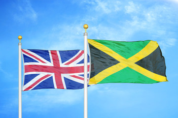 United Kingdom and Jamaica two flags on flagpoles and blue cloudy sky