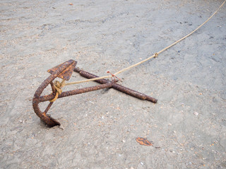 Anchor and white rope on the sand.