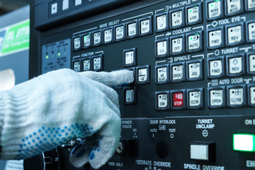 Starting the machine in production. The hand of the operator starts the CNC machine to work