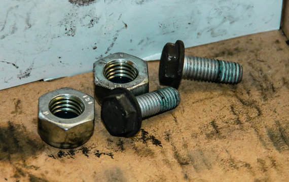 Tuercas y tornillos manchados de aceite industrial.