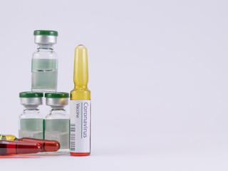 Corona Virus Vaccine label on an ampoule with another two ampoules and three vials on a white background.