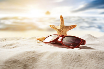 Sun glasses and starfish on beach.