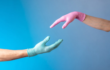 Two hands in rubber medical gloves. Relationships between people. Protection, isolation and distance during the pandemic