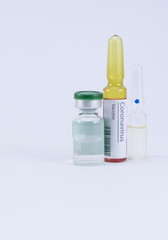Two generic ampoules with one having Corona Virus Vaccine label and an a medicine vial for its cure.