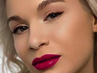 Naklejka premium Close-up beauty of a female face with fashion evening make-up. Black liner on the eyes and extremely long eyelashes, on full lips matte scarlet lip color. Well-groomed skin after spa. red lipstick
