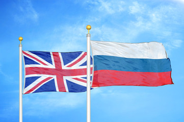 United Kingdom and Russia two flags on flagpoles and blue cloudy sky