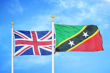 United Kingdom and Saint Kitts and Nevis two flags on flagpoles and blue cloudy sky