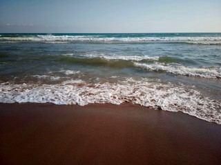 Seething seascape with sandy beach, blue sky. Copyspace.