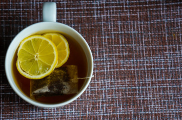a cup of black strong tea with lemon and tea bag, against the virus and the common cold