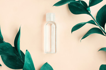 Herbal skincare, plastic bottle of cleansing cosmetic lotion top view pink background with fresh leaves, pastel colors, hydrating botanical spa product. 
