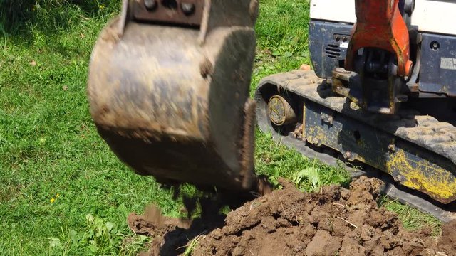 A power shovel digging a pit in a lawn