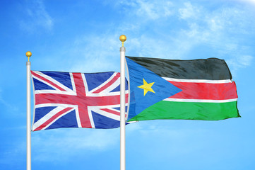 United Kingdom and South Sudan two flags on flagpoles and blue cloudy sky