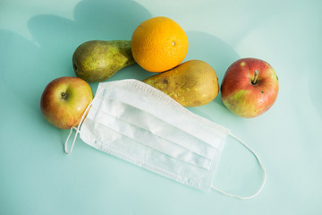 Fruit and protective mask on a mint background, fruit harvest, protection from coronavirus, fruit...