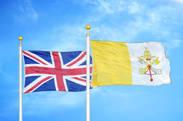 United Kingdom and Vatican two flags on flagpoles and blue cloudy sky