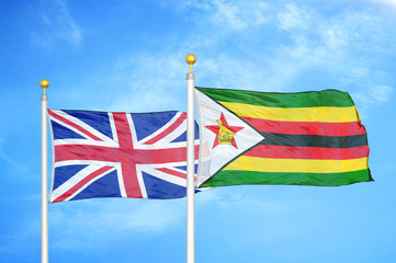 United Kingdom and Zimbabwe two flags on flagpoles and blue cloudy sky