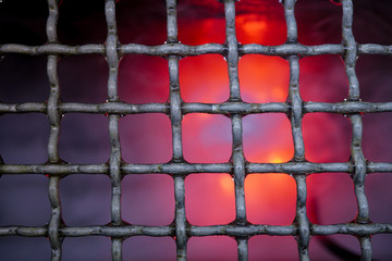 steel grate for grilling food on Smoke dry ice and red  and orange light color background .  Can use as food background                    
