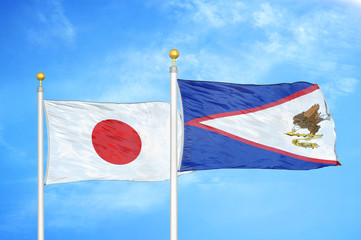 Japan and American Samoa two flags on flagpoles and blue cloudy sky
