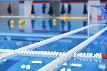 Swimming pool lane lines and floating on a still water with polo balls in background before a match