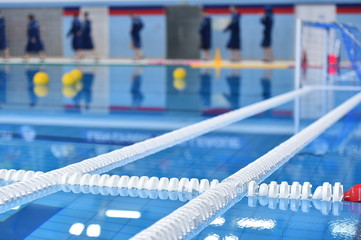 Swimming pool lane lines and floating on a still water with polo balls in background before a match