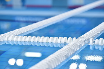 Swimming pool lane lines and floating on a still water with polo balls in background before a match