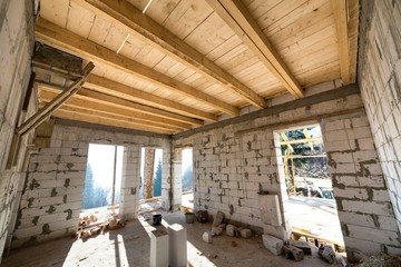 House room interior under construction and renovation. Energy saving walls of hollow foam insulation blocks, wooden ceiling beams and roof frame.