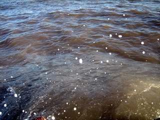 Fototapeta premium A splash of sea water on a stone pier with lots of foam and spray on a Sunny day against a flat horizon.