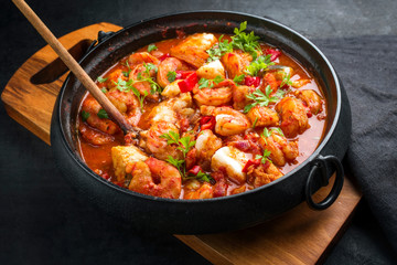 Traditional American fish stew cioppino with prawns, and fish as closeup in a modern design...