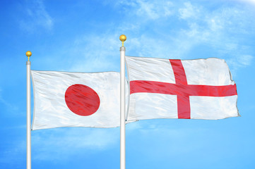 Japan and England two flags on flagpoles and blue cloudy sky