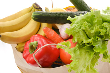 pepper, bananas, cucumber, lettuce, carrots, fresh vegetables in a paper bag on a white