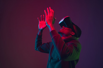 African-american man's portrait in VR-headset isolated on gradient studio background in neon light....