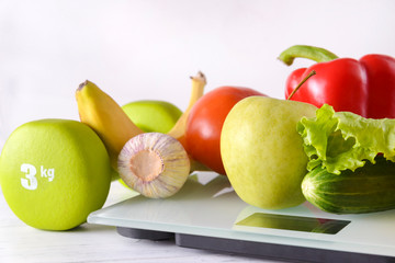 fruits and vegetables, dumbbell, are placed on white electronic scales