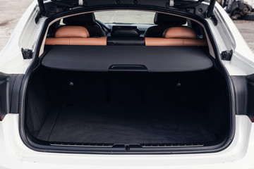 Open empty trunk of a white car. Black and brown leather car interior. Modern car illuminated dashboard. Luxurious car instrument cluster. Close up shot of automobile instrument panel © svetlichniy_igor