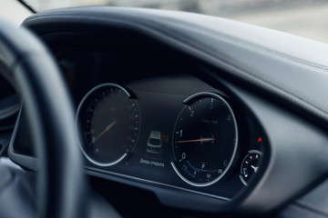 Glowing beautiful dashboard of a modern expensive car. The interior of the car. The foreground is blurred. Modern car interior details. Car detailing. Selective focus