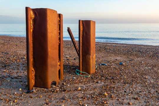 Rotten iron structure forming part of sea defences on a shingle beach