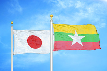 Japan and Myanmar two flags on flagpoles and blue cloudy sky