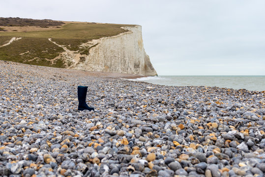 Lone boot on a deserted beach under overcast sky