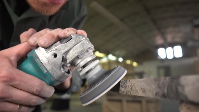  Worker in a green jacket and beard polishes a marble table in a factory. Super Slow Motion