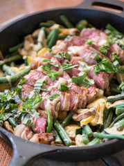 Steak skillet with fresh veggies served and cooked in a cast iron pan with basil and a tahini dressing for a healthy dinner