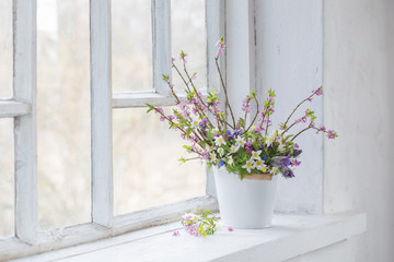 Fototapeta na wymiar spring flowers in white bucket on old white windowsill