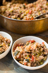 A casserole with rice and tomatoes and beans made in a copper pot and served in white dishes for a healthy meal