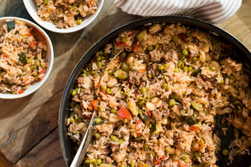 A casserole with rice and tomatoes and beans made in a copper pot and served in white dishes for a healthy meal